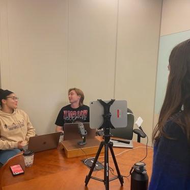 two women are sitting and talking where one lady is looking at them 