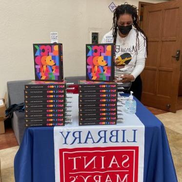 person standing next to a pile of books