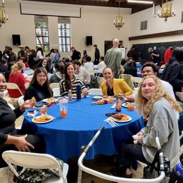 group of people standing around a table and eating